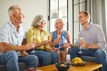 Group of contemporary adult people enjoying champagne during party at home, copy space