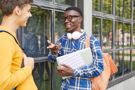 Waist up portrait of African-American student talking to friend outdoors in college campus, copy spaceの写真素材