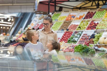 Portrait of contemporary young woman with two kids shopping together at farmers market, copy spaceの写真素材