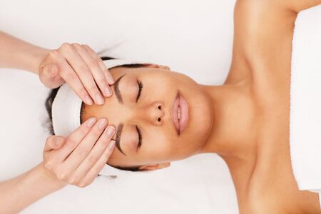 Above view portrait of beautiful mixed-race woman enjoying face massage in luxury spa, copy spaceの写真素材