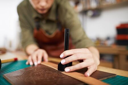 Closeup of unrecognizable artisan working with leather in small shop, copy spaceの写真素材