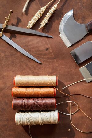 Top view background of leatherworking tools lying on wooden table in artisan atelierの写真素材