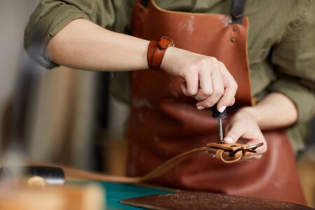 Mid section portrait of female artisan making leather belt in leatherworking shop , copy spaceの写真素材