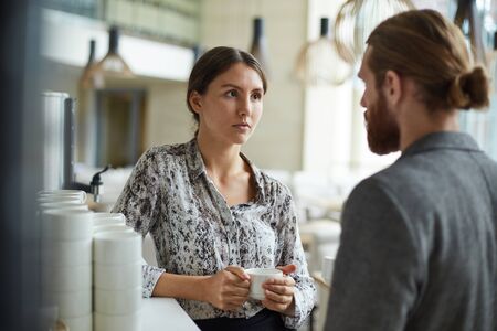 Portrait of two young business people , man and woman, talking at coffee break in office, copy spaceの写真素材