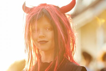 Head and shoulders portrait of cute little girl wearing Halloween costume looking at camera while posing outdoors lit by sunlight, copy spaceの写真素材