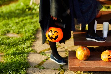 Closeup of unrecognizable child holding Halloween basket shaped as Jack o lantern while trick or treating, copy spaceの写真素材
