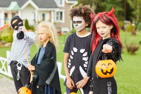 Group of children trick or treating on Halloween, all wearing costumes while posing outdoorsの写真素材