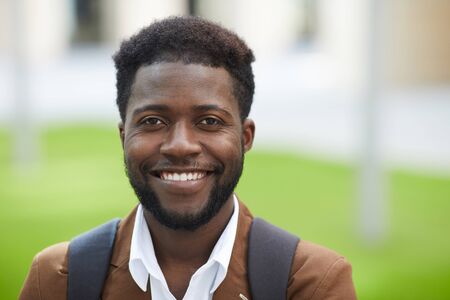 Head and shoulders portrait of handsome African-American man smiling happily at camera while posing...