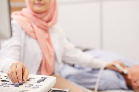 Close up of unrecognizable female doctor using ultrasound machine while examining senior patient in clinic, copy spaceの写真素材