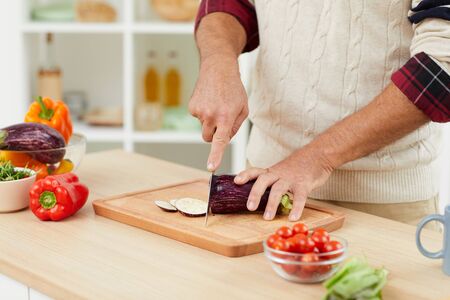 Close up of unrecognizable man cutting vegetables while cooking healthy salad in kitchen, copy spaceの写真素材