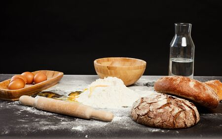 Background image of traditional bread making ingredients on bakers table against black, copy spaceの写真素材