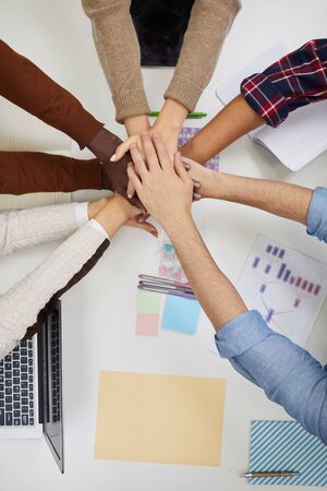 Top view of multi-ethnic business team staking hands over meeting table in office, copy spaceの写真素材