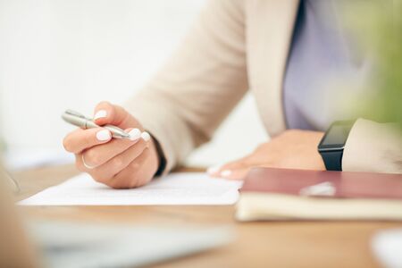 Close up of unrecognizable businesswoman signing document while working at desk in office, focus on...