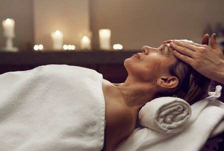 Side view portrait of elegant senior woman enjoying facial massage at luxury SPA center, copy spaceの写真素材