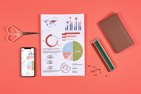 Above view flat lay of business data charts and office supplies over coral background, copy spaceの写真素材