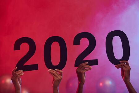 Background image of hands holding 2020 during Christmas party in nightclub, copy spaceの写真素材