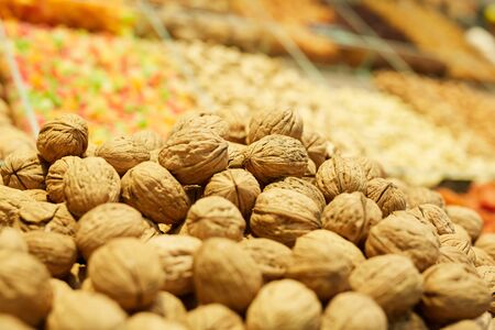 Warm-toned background of heap of walnuts on dried fruit stand in farmers market or supermarket, copy spaceの写真素材
