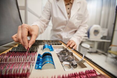 Close up of unrecognizable female optometrist choosing lenses for trial frame during glasses fitting in ophthamology clinic, copy spaceの写真素材