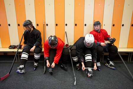 High angle view at female hockey team putting on gear in locker room while preparing for match or practice, copy spaceの写真素材