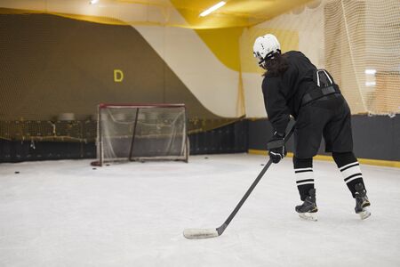 Back view portrait of unrecognizable hockey player leading pluck during practice on ice, copy space