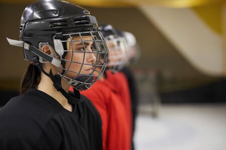 Side view portrait of female hockey team standing in line before match on rink, focus on beautiful...