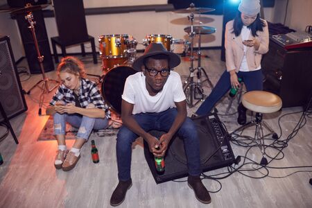 High angle portrait oif multi-ethnic group of young people sitting round instruments while relaxing...