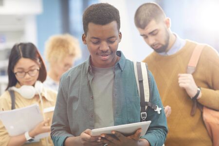 Waist up portrait of multi-ethnic group of students waking to class in sunlit college hall, focus on...