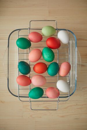Above view background of red and green hand-painted Easter eggs on drying rack over wooden table in...
