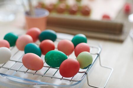 Close up background image of red and green hand-painted Easter eggs on drying rack in art studio,...