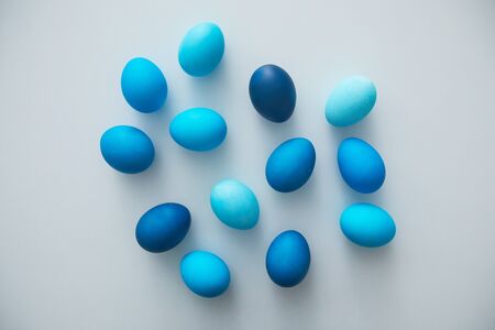Above view of hand-painted blue Easter eggs arranged in minimal composition on white background, copy spaceの写真素材