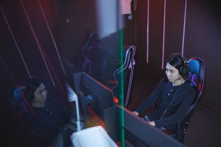High angle view at young Asian man using computer in futuristic cyber interior, copy space