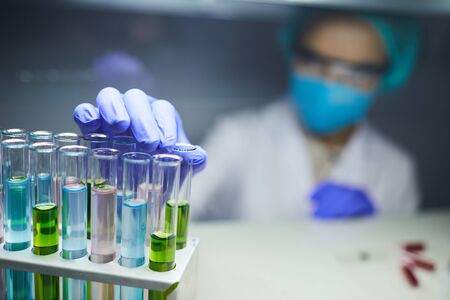 Close up of scientist taking test tube with colored liquid while working on bio research in...