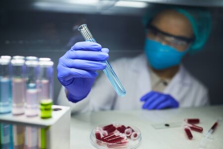 Close up of scientist holding test tube with blue liquid while working on bio research in laboratory, copy spaceの写真素材