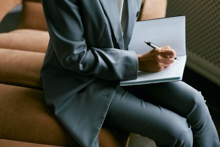 High angle close up of unrecognizable mature businesswoman writing in planner, copy space