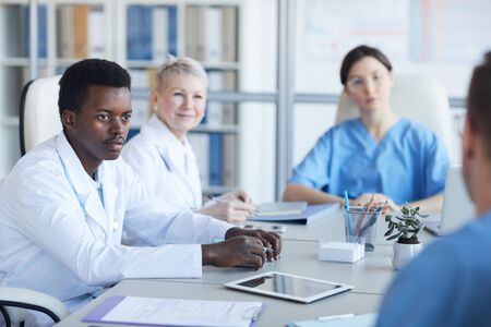 Portrait of young African-American doctor listening to colleague committee during medical conference, copy spaceの写真素材