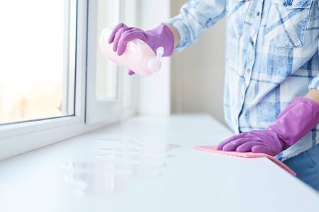 Cropped portrait of unrecognizable woman washing windows during Spring cleaning, focus on female...