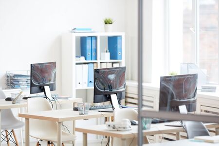 Background image of empty office desks in row set shot from behind glass door, copy space