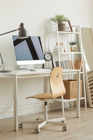 Vertical background image of cozy home office workplace with minimal design, focus on wooden char against computer desk in foreground, copy spaceの写真素材