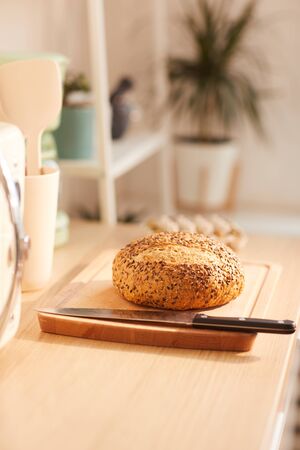 Vertical background image of fresh homemade bread on wooden table in kitchen interior, copy space