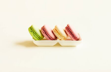Minimal composition of delicious pastel-colored macaroons in row on china platter over white background, copy spaceの写真素材