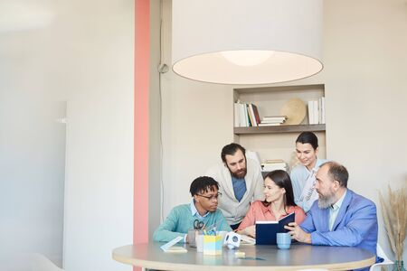 Group of five modern office workers gathered together discussing issues of new big project, copy...
