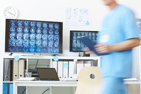 Background image of modern computer equipment with CT brain scans on screens at work station and...