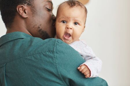 Back view portrait of young African-American father holding son with cute baby looking at camera...