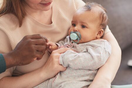 Warm-toned portrait of happy interracial family enjoying time together at home, with...