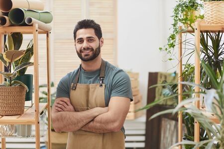 Waist up portrait of handsome bearded man using digital tablet while counting stock in flower store, copy spaceの写真素材