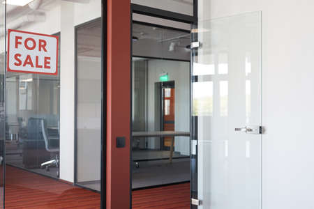 Graphic background image of empty office interior with red For sale sign on glass door, copy spaceの写真素材