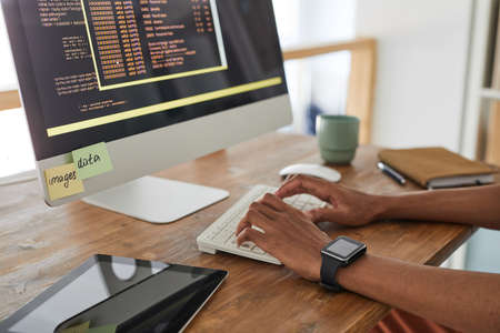 Close up of African-American computer programmer typing on keyboard with black and orange...