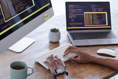 Background image of male hands typing on keyboard while working on computer code in IT development...