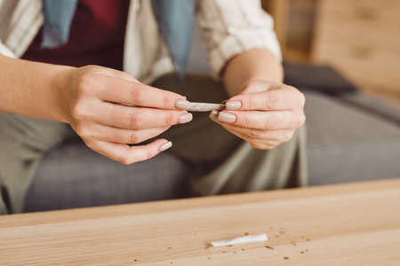 Warm-toned close up of unrecognizable adult woman taking marijuana for medicinal purposes in cancer recovery, copy spaceの写真素材