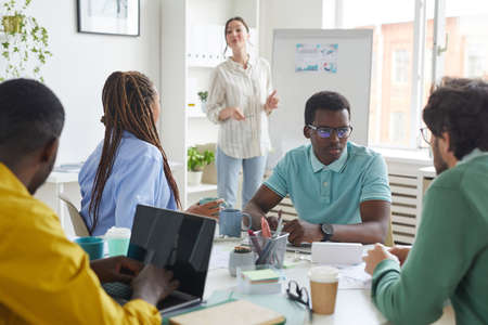 Portrait of multi-ethnic business team discussing project while sitting at table in conference room...